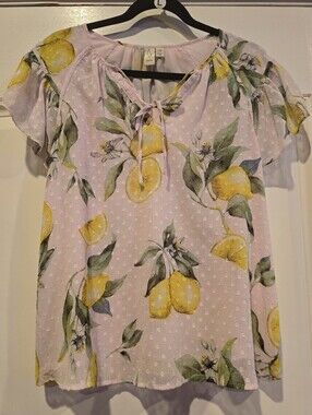 Joie blouse features a vibrant yellow lemon print against a soft pink background